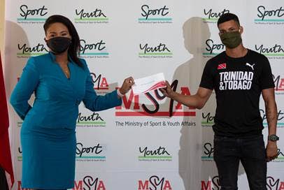 Minister of Sport and Youth Affairs, left, presents a cheque to boxer Michael Alexander, at the ministry's office on April 27. - Photo courtesy the MSYA