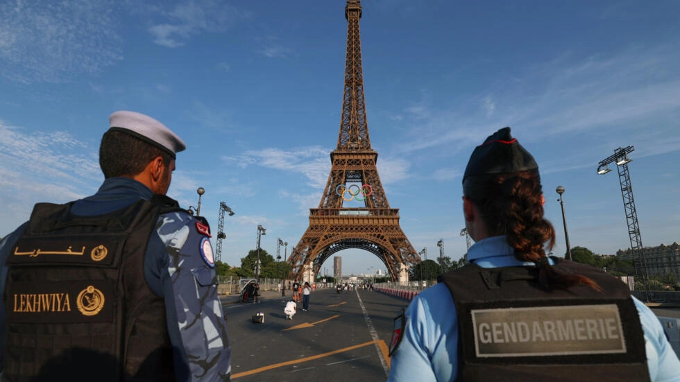 A French policewoman and a Qatari policeman stand guard near the Eiffel Tower as security preparations step up for the Paris Olympics. © Emmanuel Dunand, AFP (Image obtained at www.france24.com)